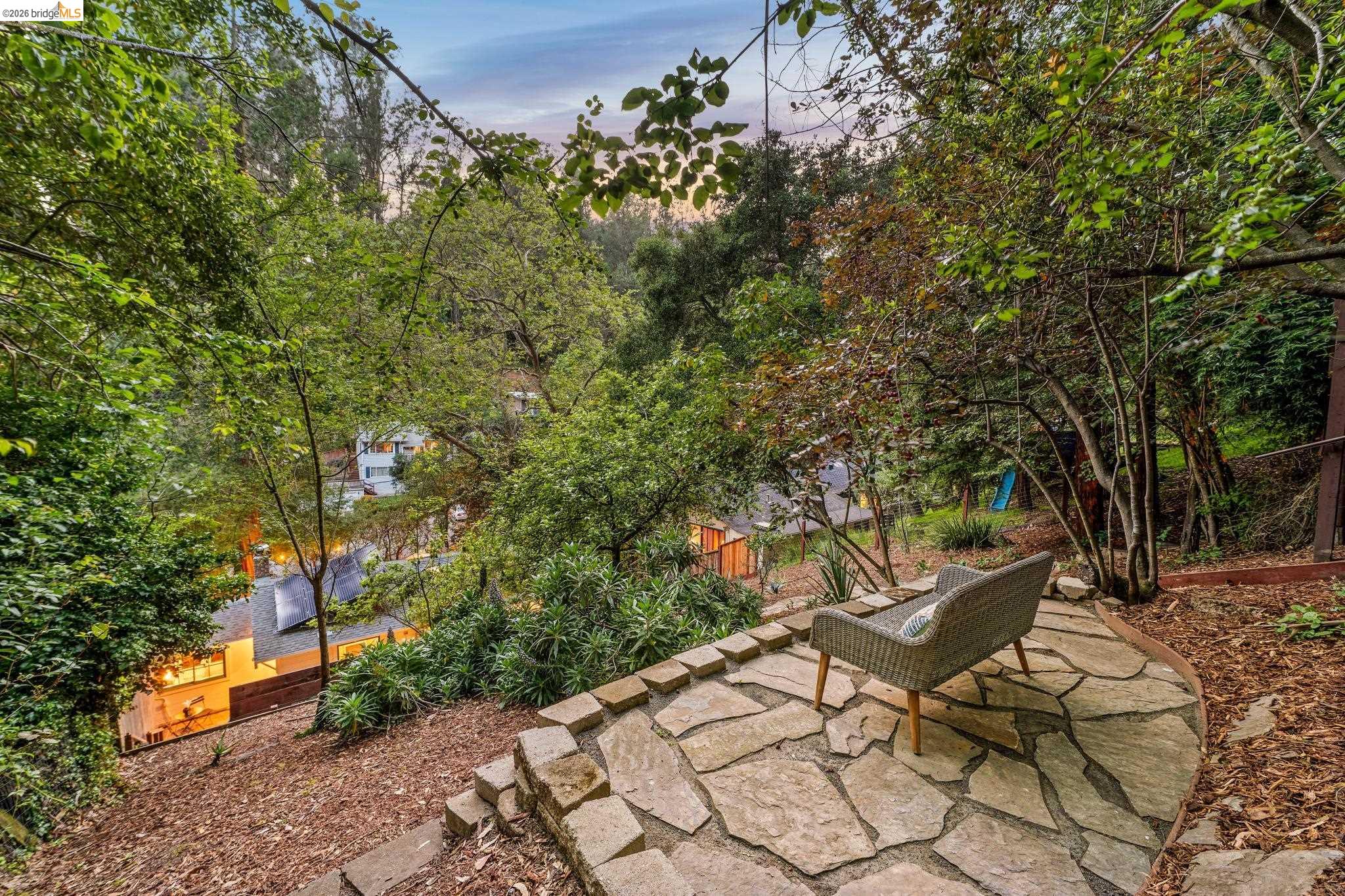 6400 Pinehaven Road Oakland, CA 94611 - Photo 73 of 78 Sloped backyard featuring a flagstone patio, mature trees, natural landscaping, and partial distant structures