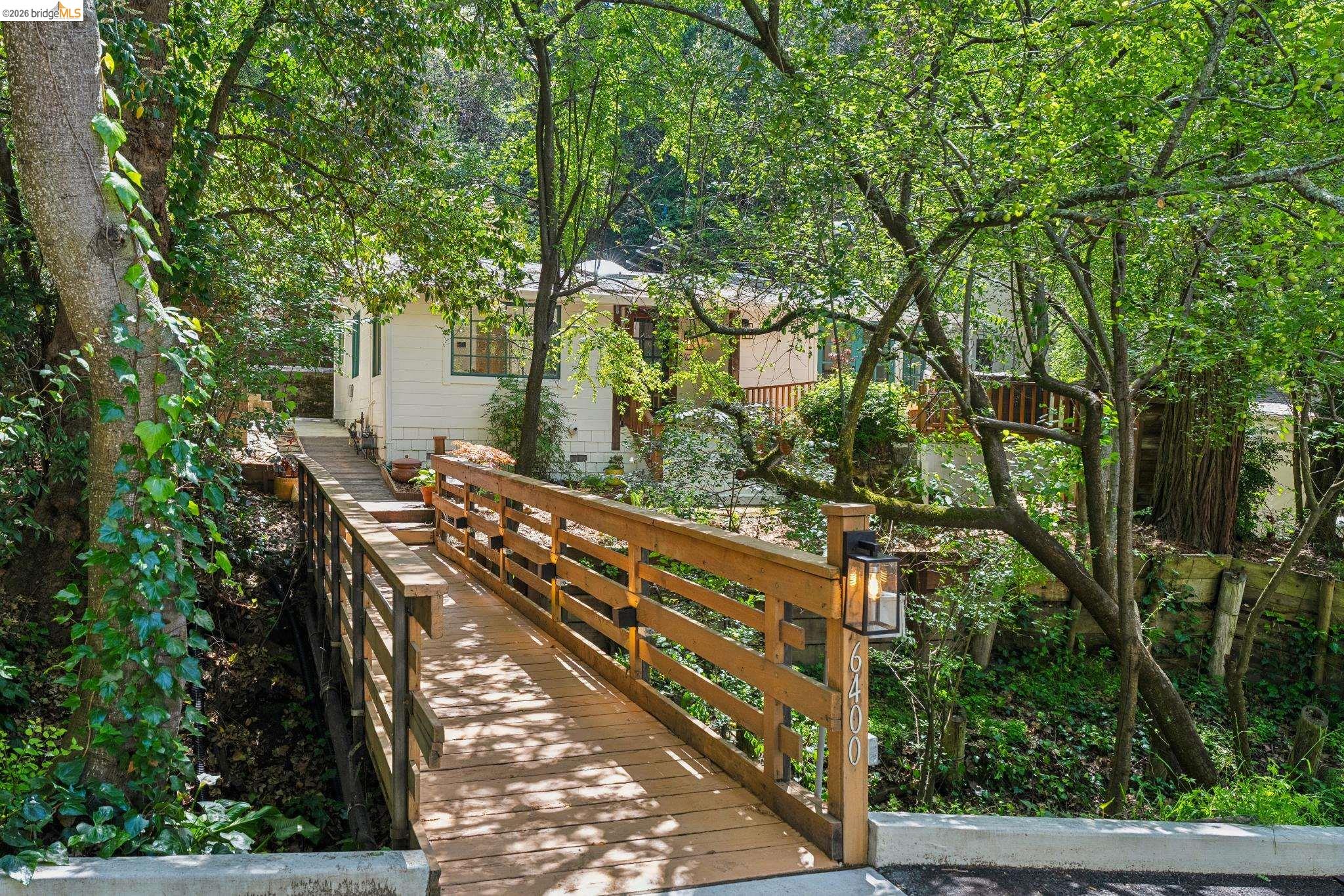 6400 Pinehaven Road Oakland, CA 94611 - Photo 75 of 78 Wood bridge entry with dark metal post-mounted light fixture leading to a white exterior home