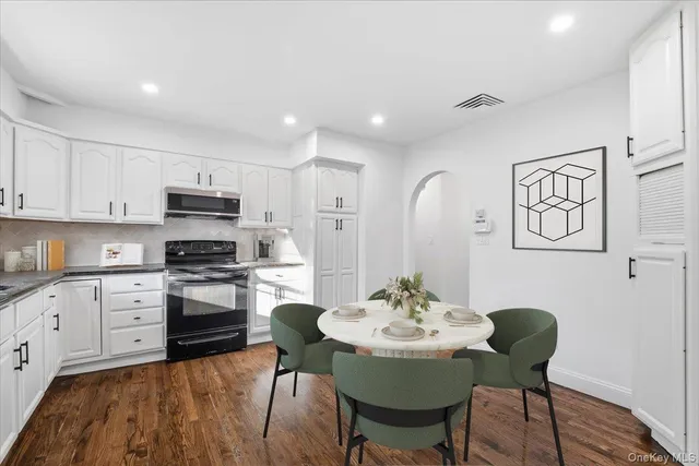 a kitchen with stainless steel appliances granite countertop a dining table chairs a stove top oven with wooden floor