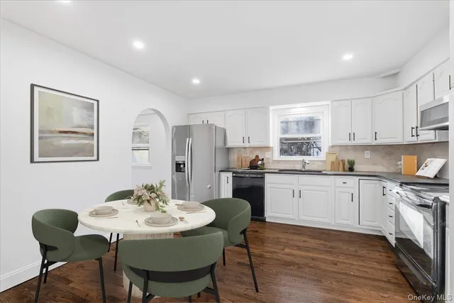 a kitchen with stainless steel appliances kitchen island granite countertop a dining table chairs and a refrigerator