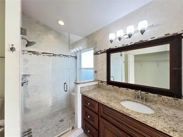 a bathroom with a granite countertop sink a mirror and a shower