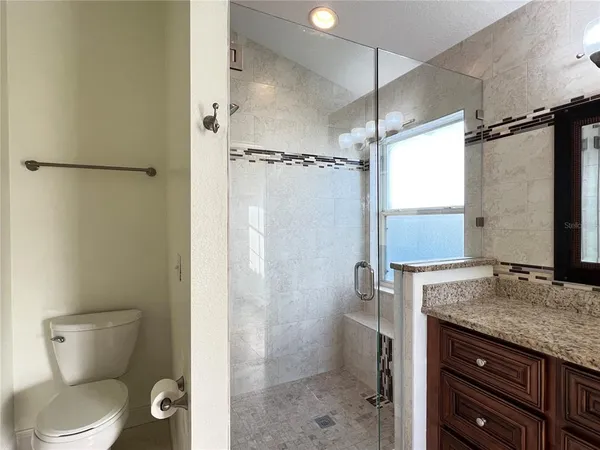 a bathroom with a granite countertop sink toilet and shower