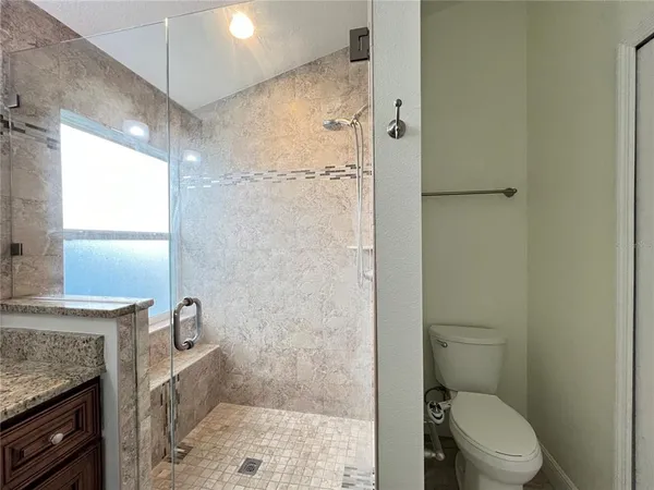 a bathroom with a granite countertop shower a toilet and a sink