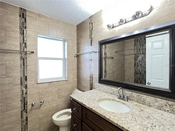 a bathroom with a granite countertop sink toilet a mirror and shower