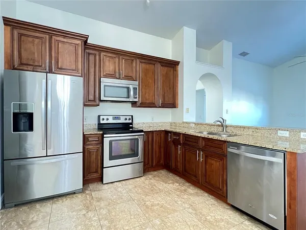 a kitchen with granite countertop a refrigerator stove and microwave
