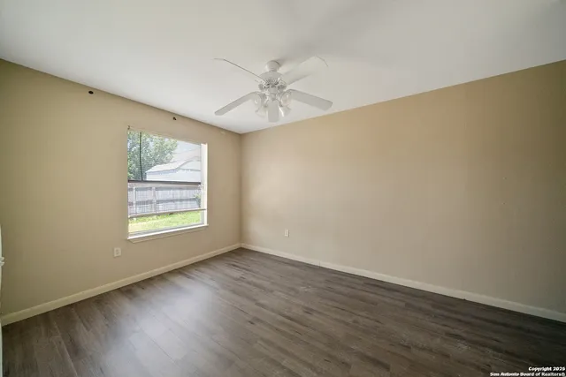 a view of an empty room with wooden floor and a window