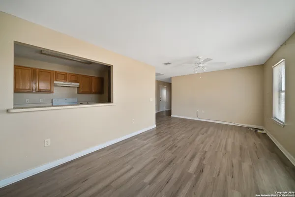 a view of empty room with wooden floor and fan