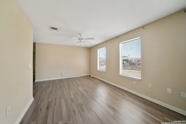 an empty room with wooden floor and windows