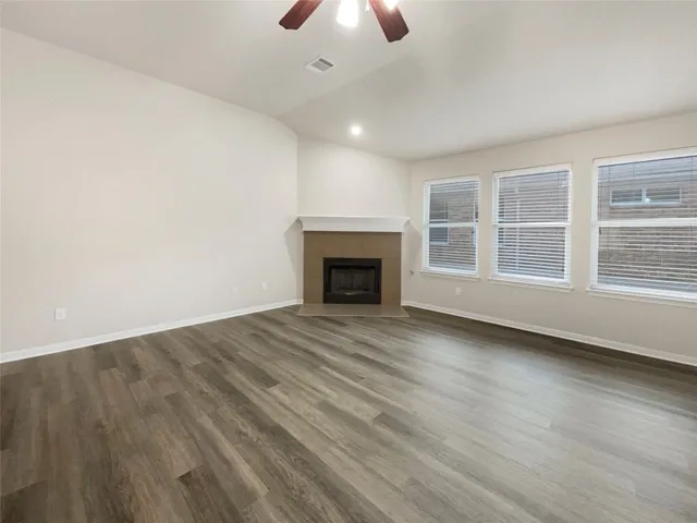an empty room with chandelier fan and windows