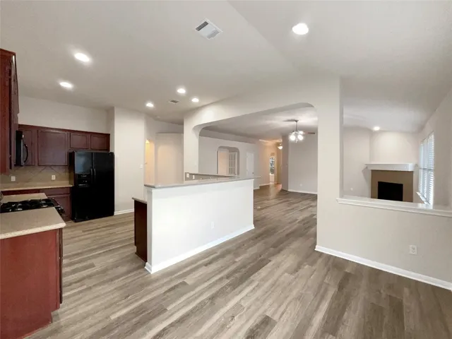 a view of kitchen with kitchen island wooden floor and stainless steel appliances