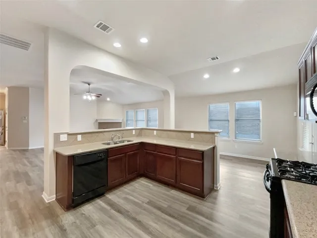 a large kitchen with stainless steel appliances granite countertop a sink and wooden cabinets