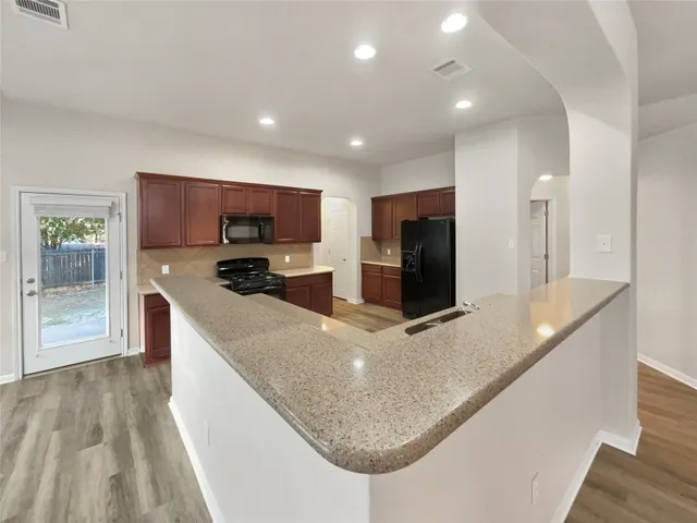 a large kitchen with stainless steel appliances a large counter top and a refrigerator