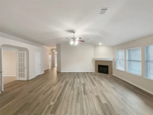 a view of an empty room with wooden floor fireplace and a window