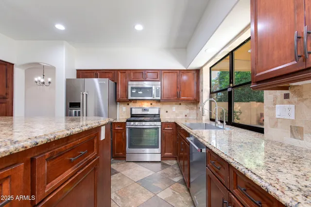 a kitchen with stainless steel appliances kitchen island granite countertop a refrigerator and a stove top oven
