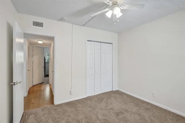 an empty room with closet and a chandelier fan
