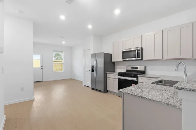 a kitchen with granite countertop a refrigerator a sink a stove a microwave and island