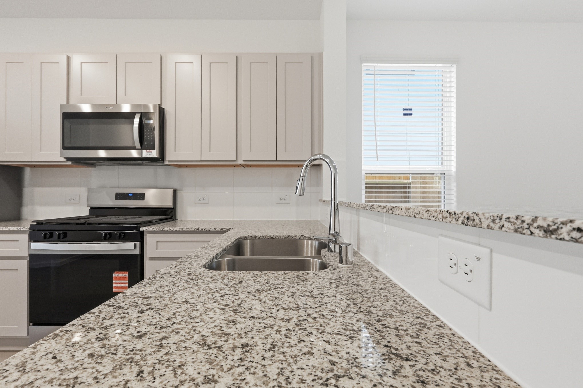 26299 Arrowleaf Drive Magnolia, TX 77355 - Photo 10 of 24 a kitchen with granite countertop a sink dishwasher stove and cabinets