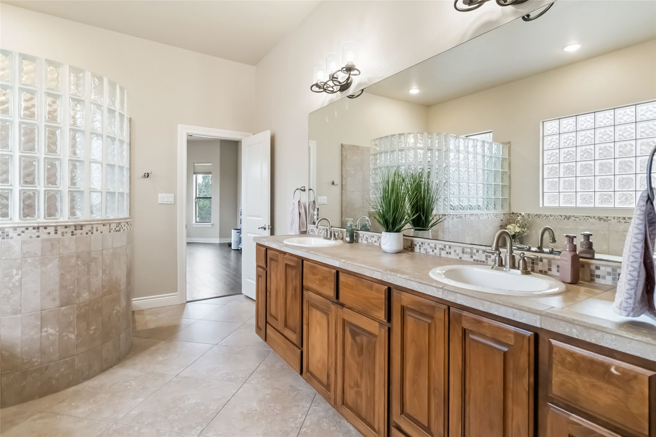 108 Standing Oak Drive Georgetown, TX 78633 - Photo 24 of 37 Well-appointed primary bathroom with double sinks, tile finishes throughout, and a walk-in shower with glass block for natural light and privacy. Separate tub and easy access to the primary closet complete the space.