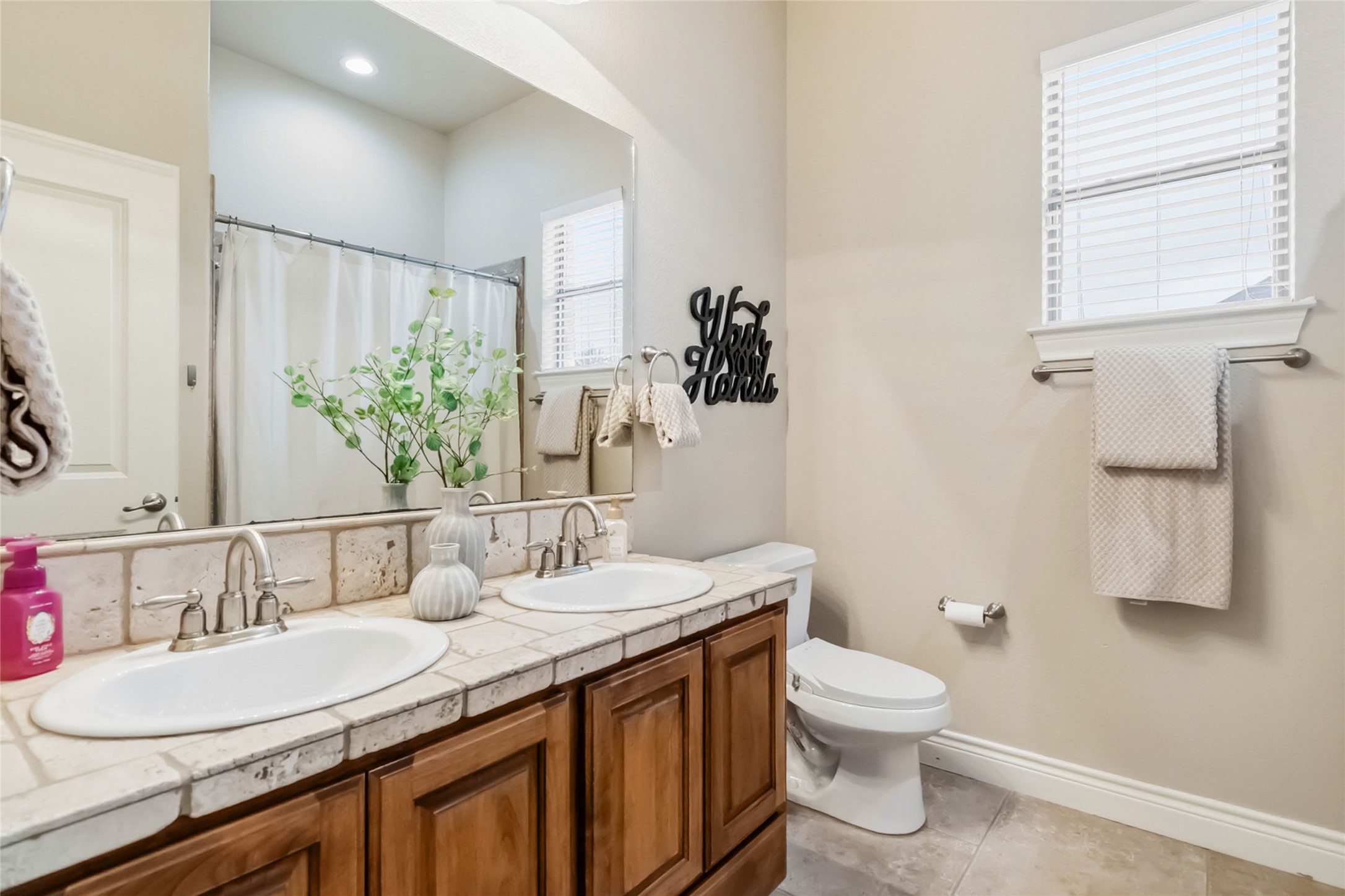 108 Standing Oak Drive Georgetown, TX 78633 - Photo 28 of 37 Secondary full bathroom with dual-sink vanity, neutral tile finishes, and a tub/shower combo. Conveniently located between Bedrooms 2 and 3.