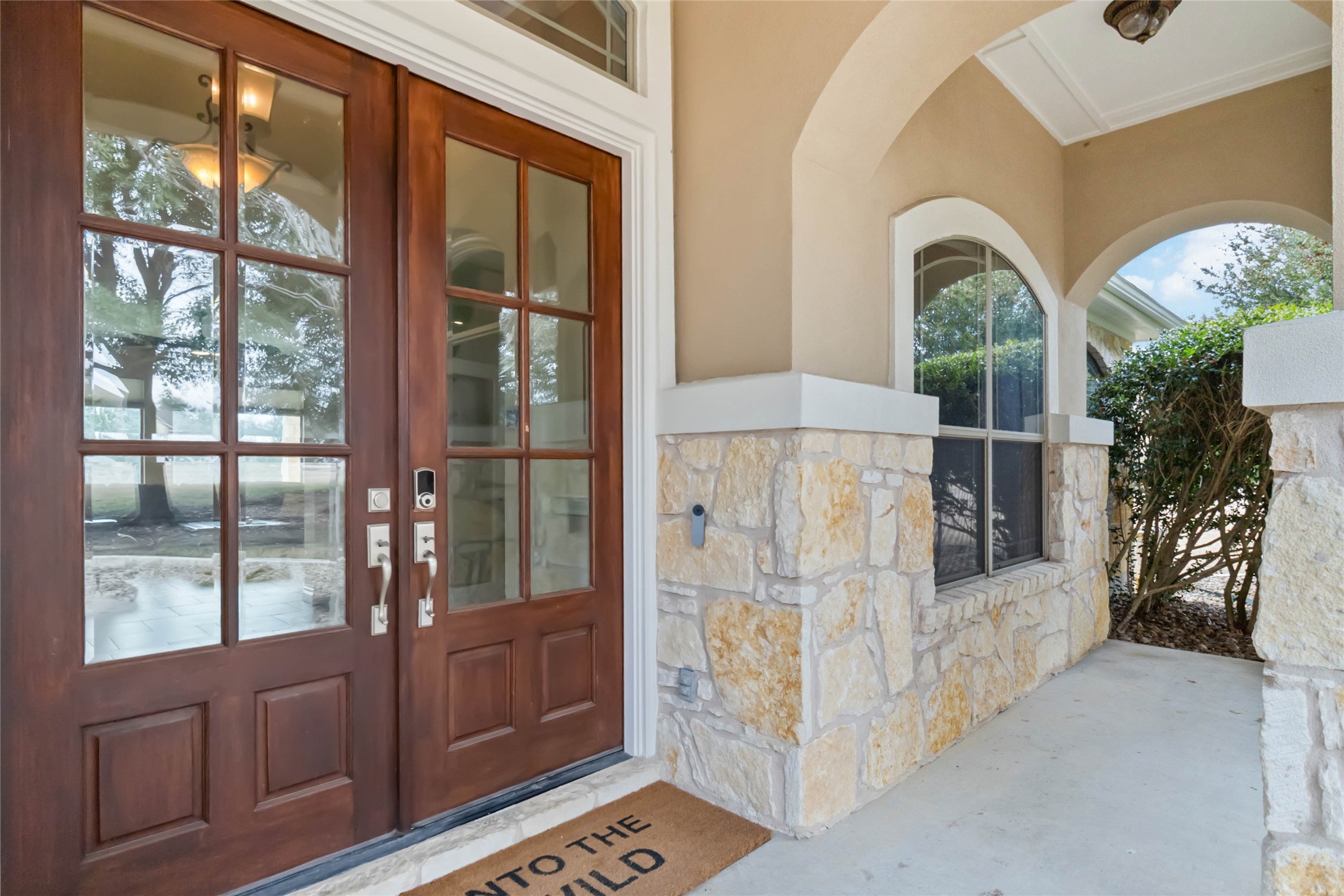 108 Standing Oak Drive Georgetown, TX 78633 - Photo 4 of 37 Rich wood double doors, arched details, and stonework highlight the home’s quality craftsmanship at the front entry.
