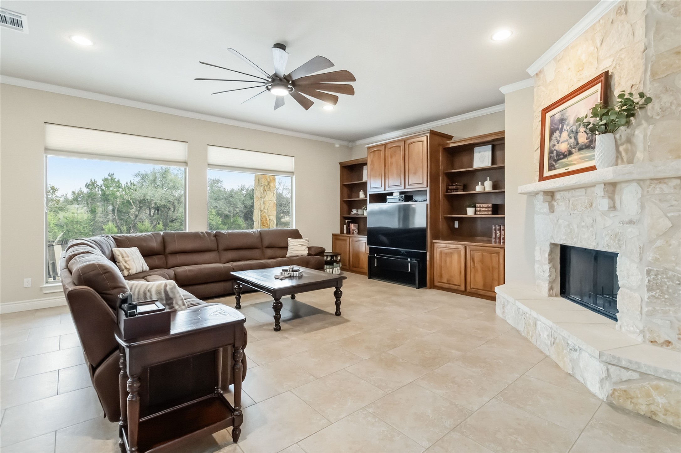 108 Standing Oak Drive Georgetown, TX 78633 - Photo 7 of 37 The living room features tile flooring, a floor-to-ceiling stone fireplace, and custom built-ins, with large windows bringing in natural light and backyard views.