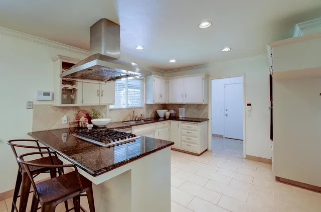 a kitchen with a stove a refrigerator and chairs