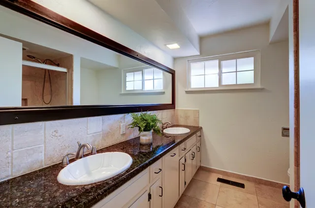 a bathroom with a granite countertop sink and a mirror