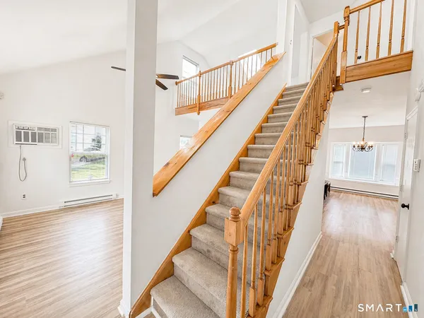 a view of staircase with lots of frames on wall and wooden floor