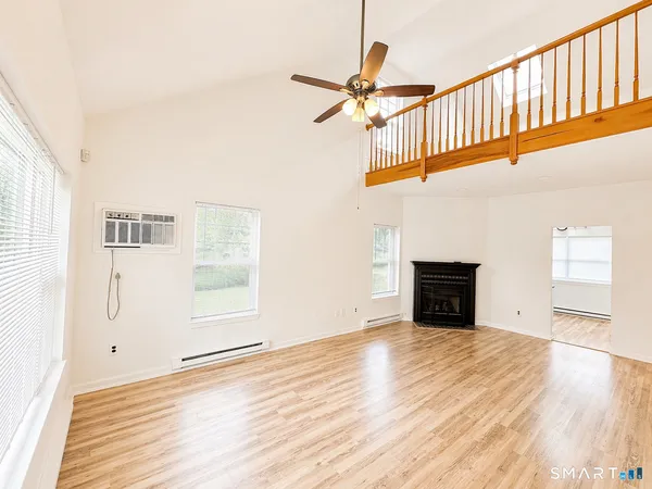 a view of an empty room with wooden floor and a window