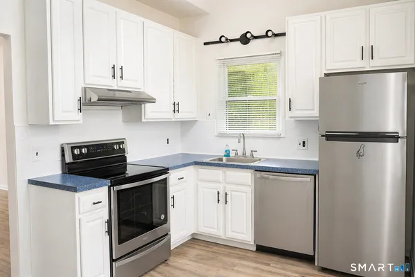 a kitchen with granite countertop white cabinets white stainless steel appliances and sink