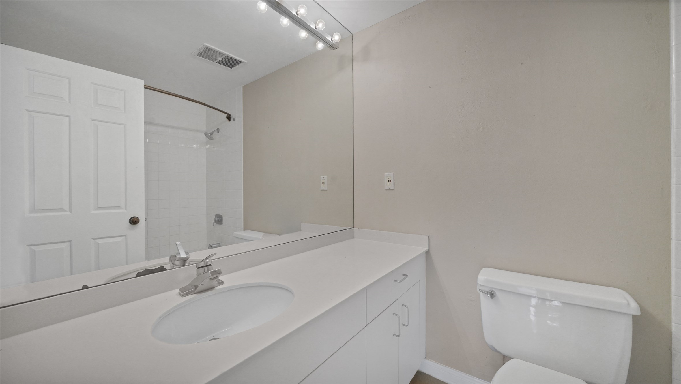 2001 Holcombe Boulevard, Unit 404 Houston, TX 77030 - Photo 11 of 33 Modern bathroom with a sleek vanity and large mirror, featuring a bathtub and shower combination. Neutral tones and ample lighting create a clean, bright atmosphere.