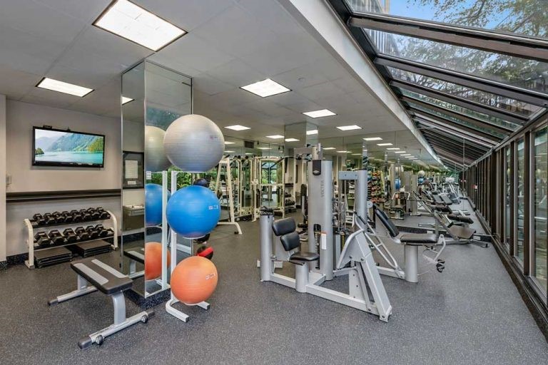 2001 Holcombe Boulevard, Unit 404 Houston, TX 77030 - Photo 31 of 33 This photo showcases a well-equipped home gym with various exercise machines, free weights, and fitness balls. The space is bright and open, featuring floor-to-ceiling windows that provide a view of the outdoors.