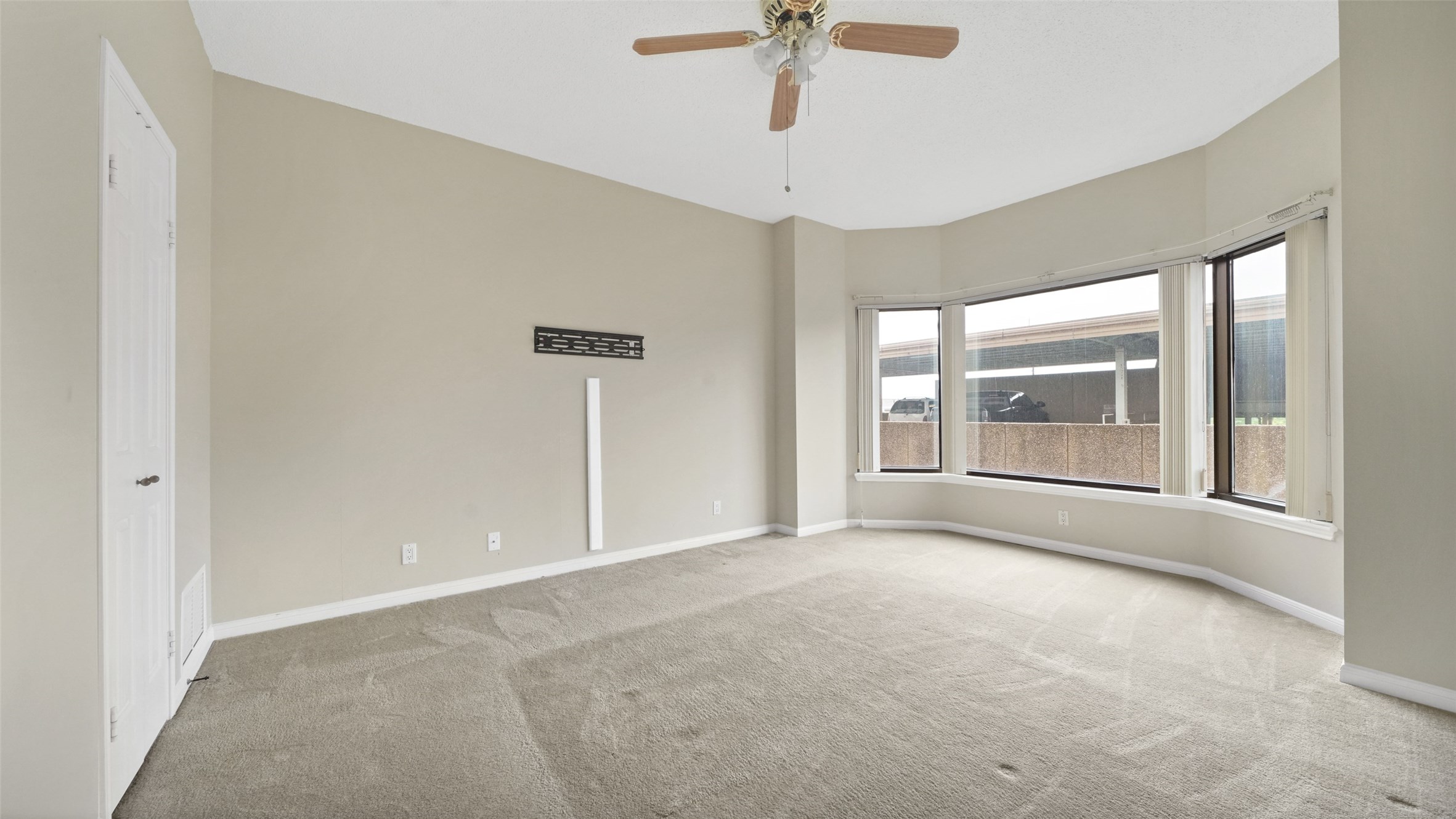 2001 Holcombe Boulevard, Unit 404 Houston, TX 77030 - Photo 10 of 33 Bright, spacious room with neutral walls and carpet, featuring a ceiling fan and large bay windows that let in ample natural light.