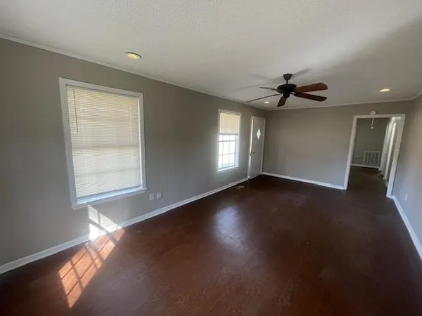 a view of an empty room with wooden floor and a window