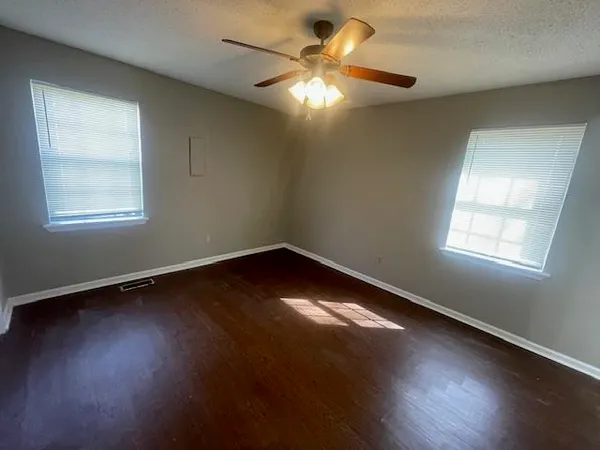 an empty room with wooden floor and windows