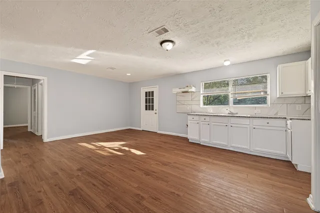a view of an empty room with a window and wooden floor