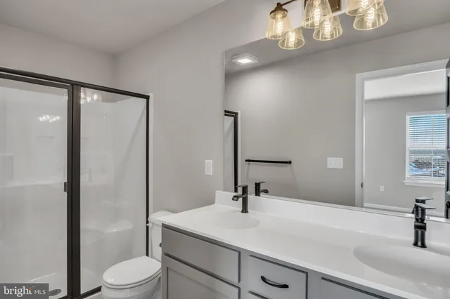 a bathroom with a sink a toilet a mirror and shower