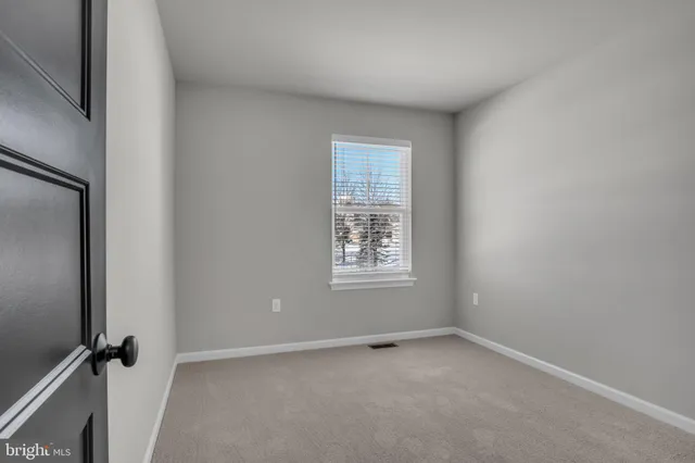 a view of an empty room with closet and a bathroom