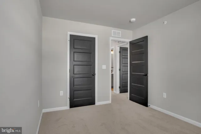 a view of an empty room with closet and a window