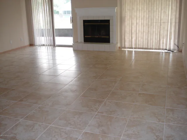 a view of an empty room with a fireplace and a window