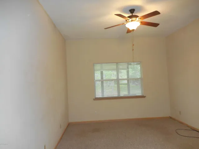 an empty room with a window and a fan