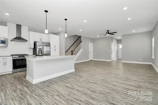 a view of a kitchen with kitchen island a sink stainless steel appliances and cabinets