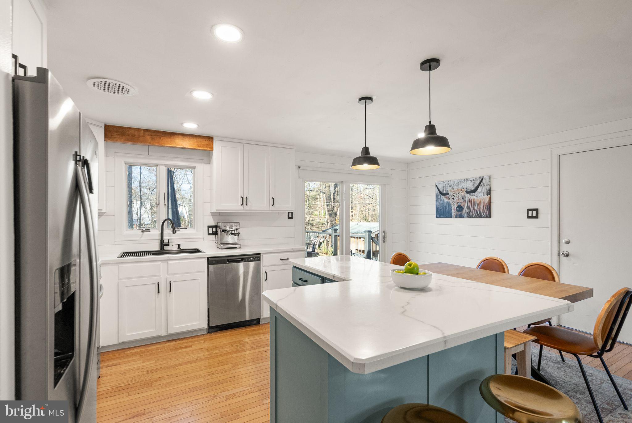 7902 Cliff Rock Court Springfield, VA 22153 - Photo 12 of 57 a kitchen with a sink a stove a refrigerator and white cabinets with wooden floor