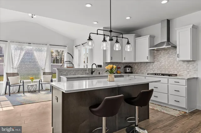 a kitchen with stainless steel appliances granite countertop a sink a stove a refrigerator and island with wooden floor