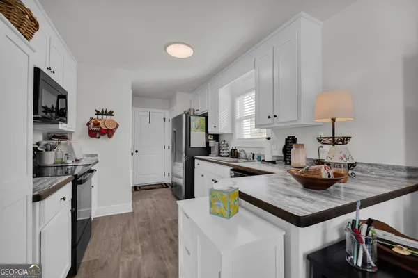 a kitchen with a sink dishwasher and white cabinets with wooden floor