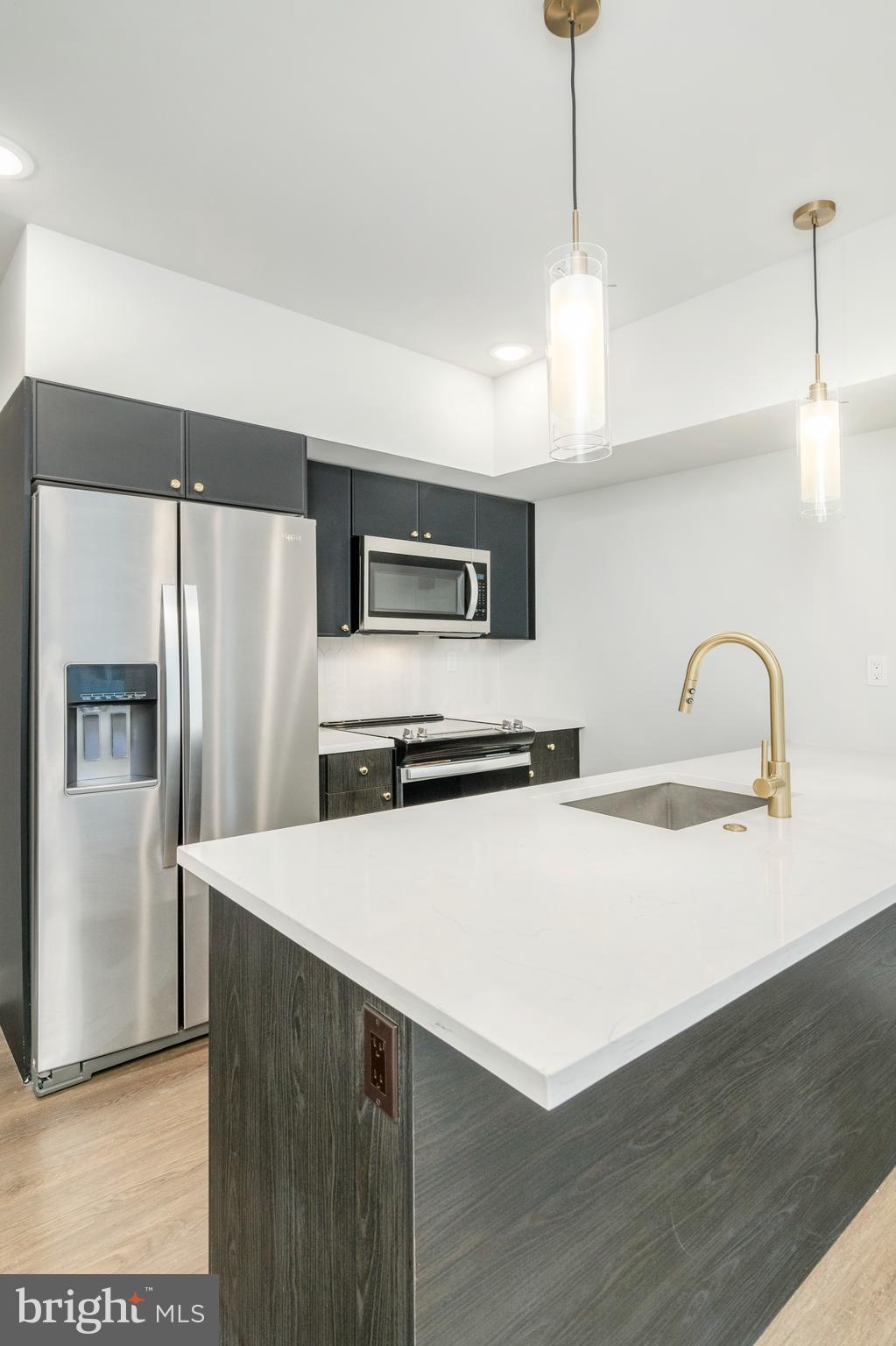 1102 Germantown Avenue, Unit 302 Philadelphia, PA 19123 - Photo 12 of 30 a kitchen with stainless steel appliances a refrigerator sink and wooden floor