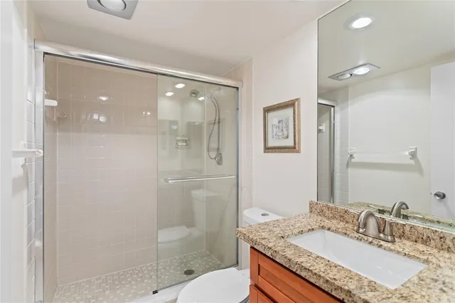 a bathroom with a granite countertop sink a mirror and a shower