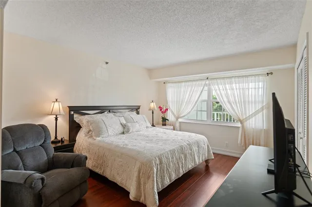 a bedroom with a bed couch and a flat tv screen on the dresser