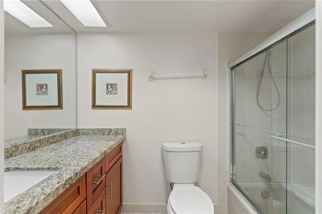 a bathroom with a granite countertop sink toilet and shower
