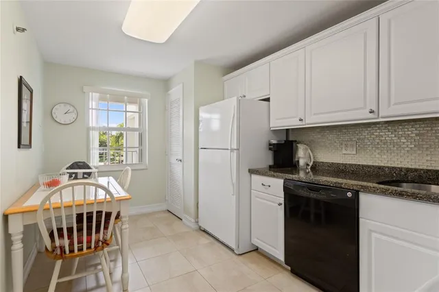 a kitchen with stainless steel appliances granite countertop a stove a refrigerator a sink a dining table and chairs with wooden floor